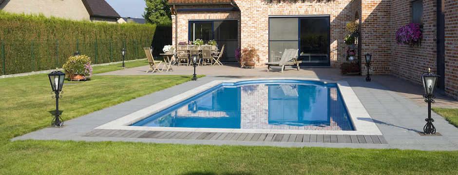 Piscine enterrée avec margelles en pierre et pelouse
